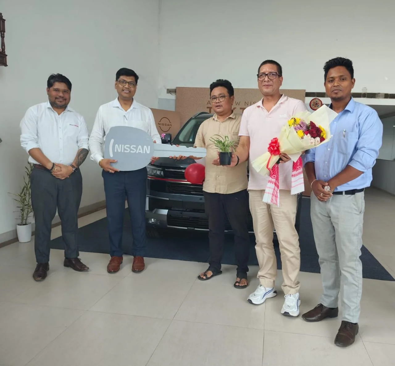 Binod Nissan team presenting a vehicle key during a customer delivery